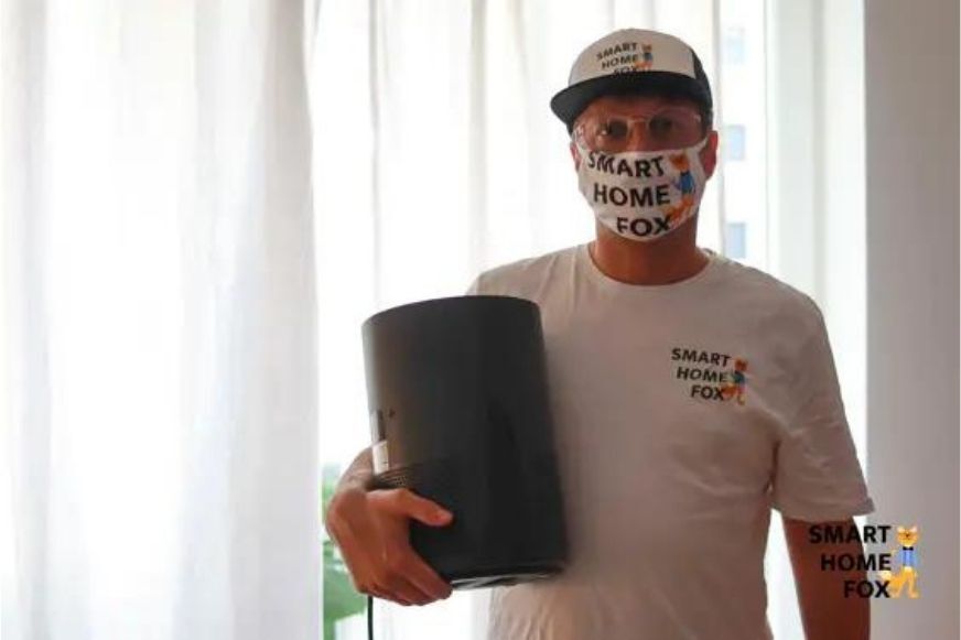 Человек держит в руке очиститель воздуха и надевает респираторную маску